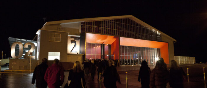 A group of people walking towards the MAC 02 at night.