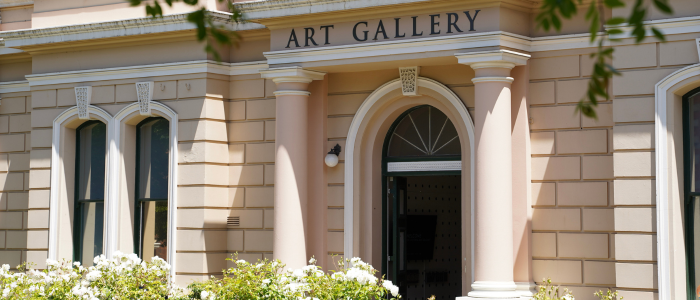 A white stoned colonial building with the words Art Gallery printed above the door.